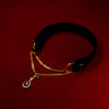 Black velvet choker with gold chain and green gemstones on a red background