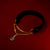 Black velvet choker with gold chain and green gemstones on a red background