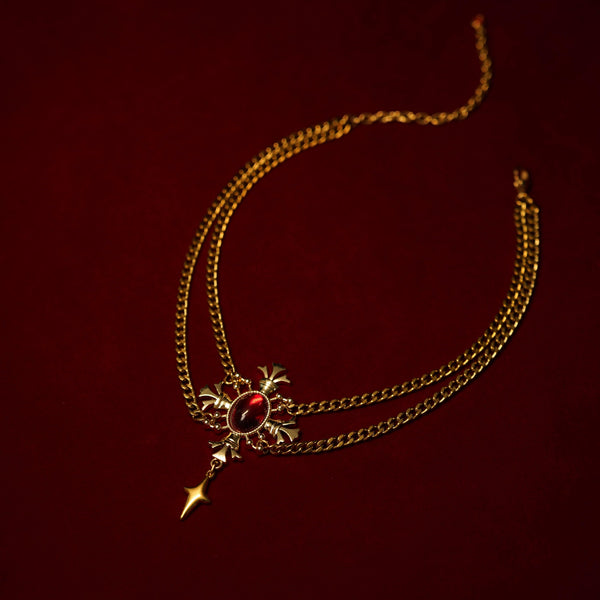 Gold necklacet with a red gemstone on a dark red background
