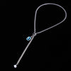 Silver chain with a blue gemstone on a black background