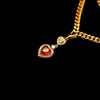 Gold necklace with a red gemstone pendant on a black background