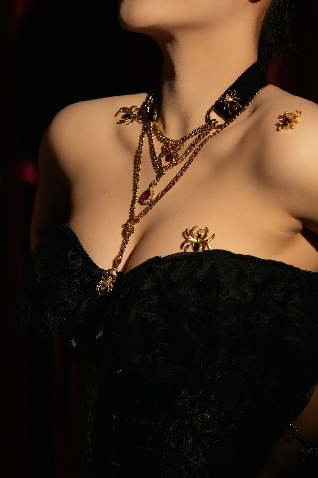 VelourBliss Halloween editorial with a black velvet choker, layered gold-tone chains and spider accents above a black lace neckline.