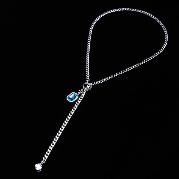 Silver chain with a blue gemstone on a black background