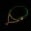 Green velvet headband with gold chain and red gemstones on a black background