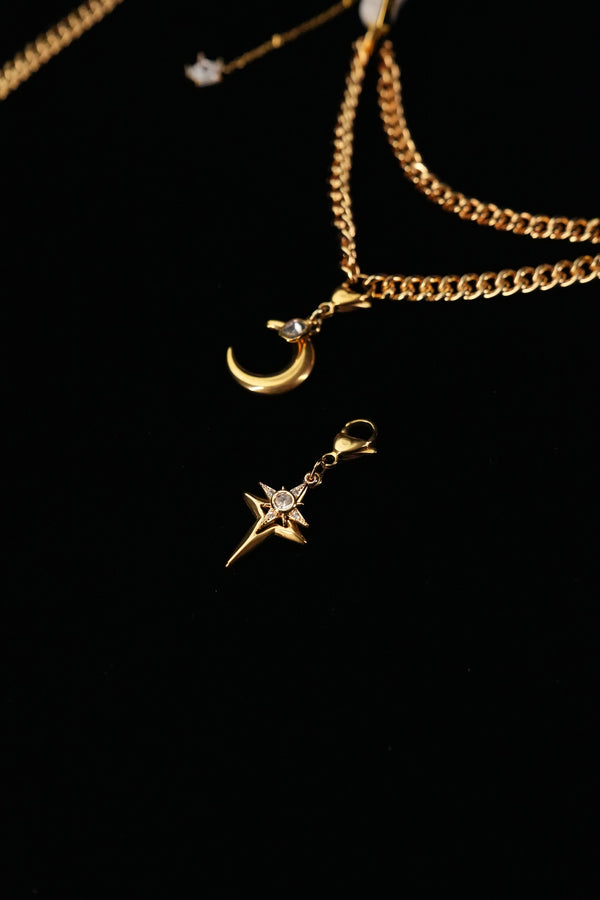 Crescent moon and cross-shaped star pendants beneath layered gold-tone chains