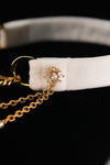 Oval floral-style ornament with clear accents on the white choker band