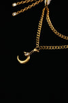Detail of layered gold-tone chains and a crescent moon charm