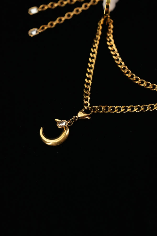 Detail of layered gold-tone chains and a crescent moon charm