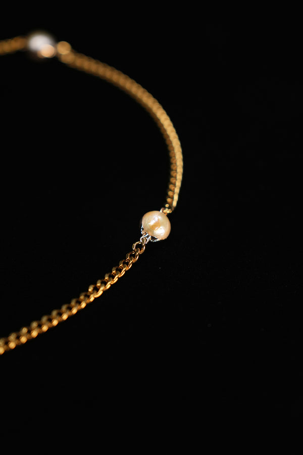Cultured pearl accent between sections of the gold-tone chain