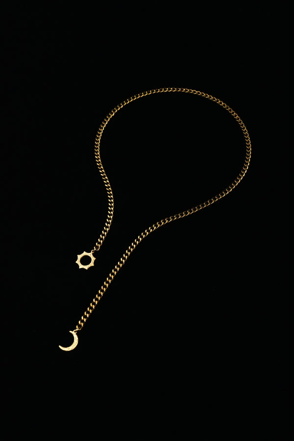 Gold-tone sun and moon necklace laid flat, showing the full chain and end details