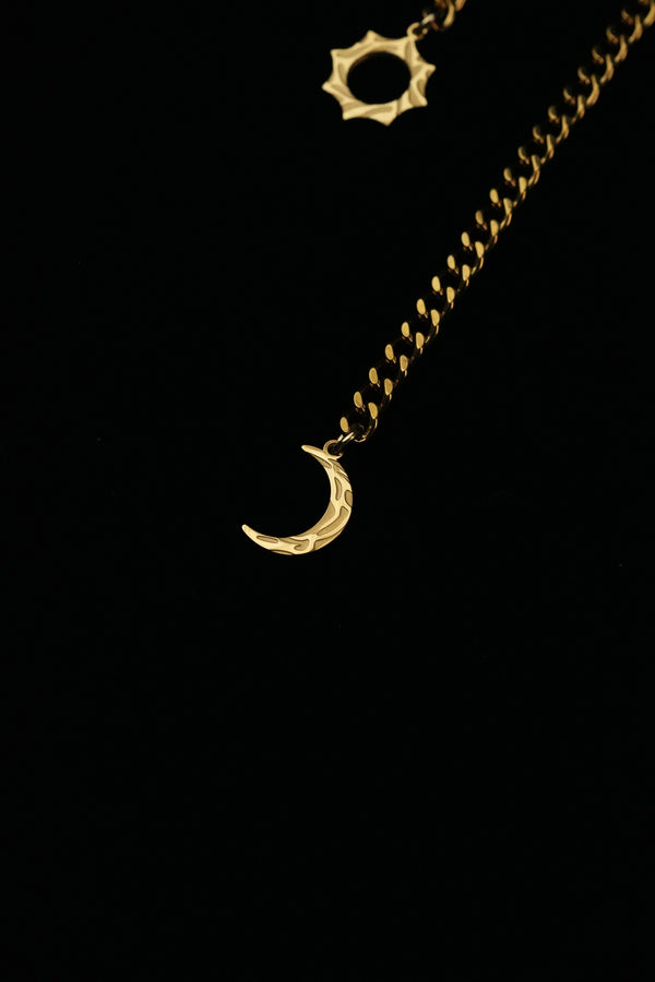 Close-up of the crescent moon charm at the end of the gold-tone necklace